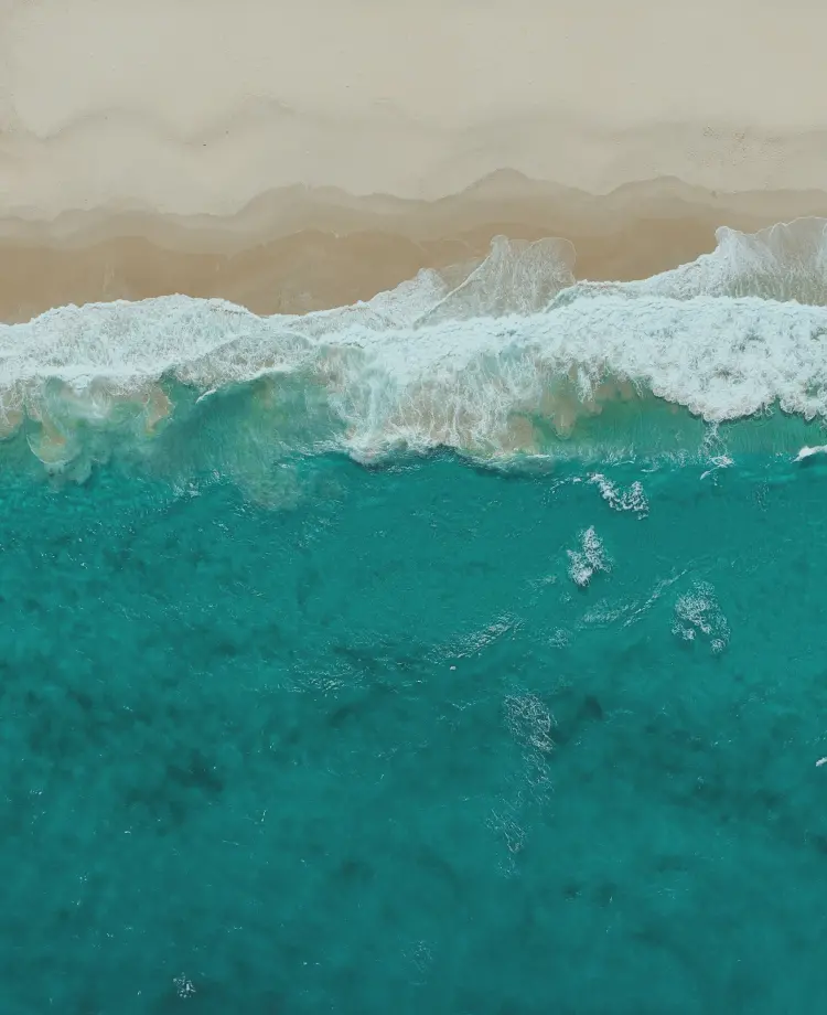 波が立つ砂浜を真上から撮った写真